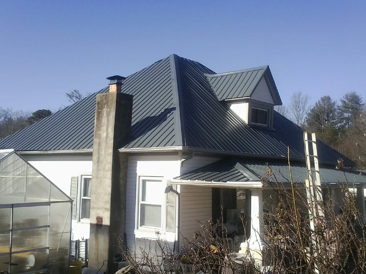 Dark blue standing seam metal roof on a white farmhouse with dormer — Slate & Tile Roof Repair by Roofing Brothers in Chula Vista