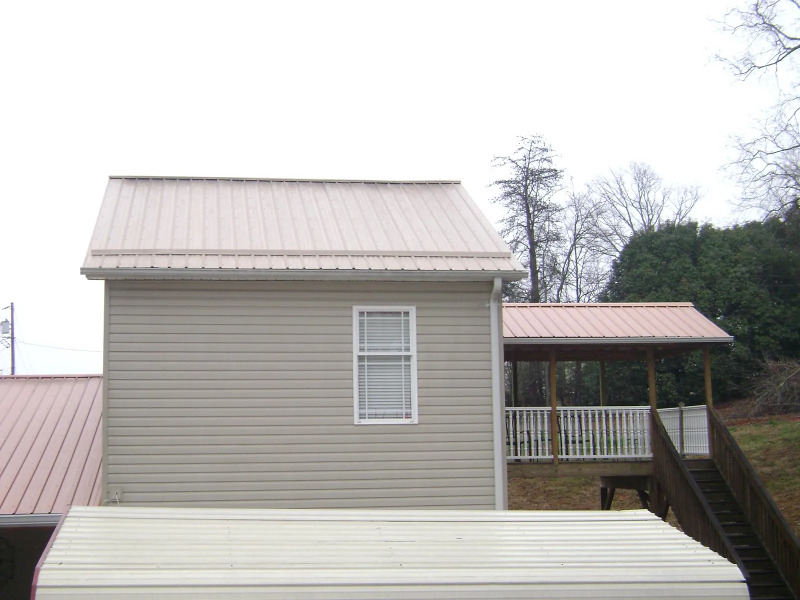 Tan metal roofs on a two story addition and attached porch, from a Roof Replacement job in Chula Vista