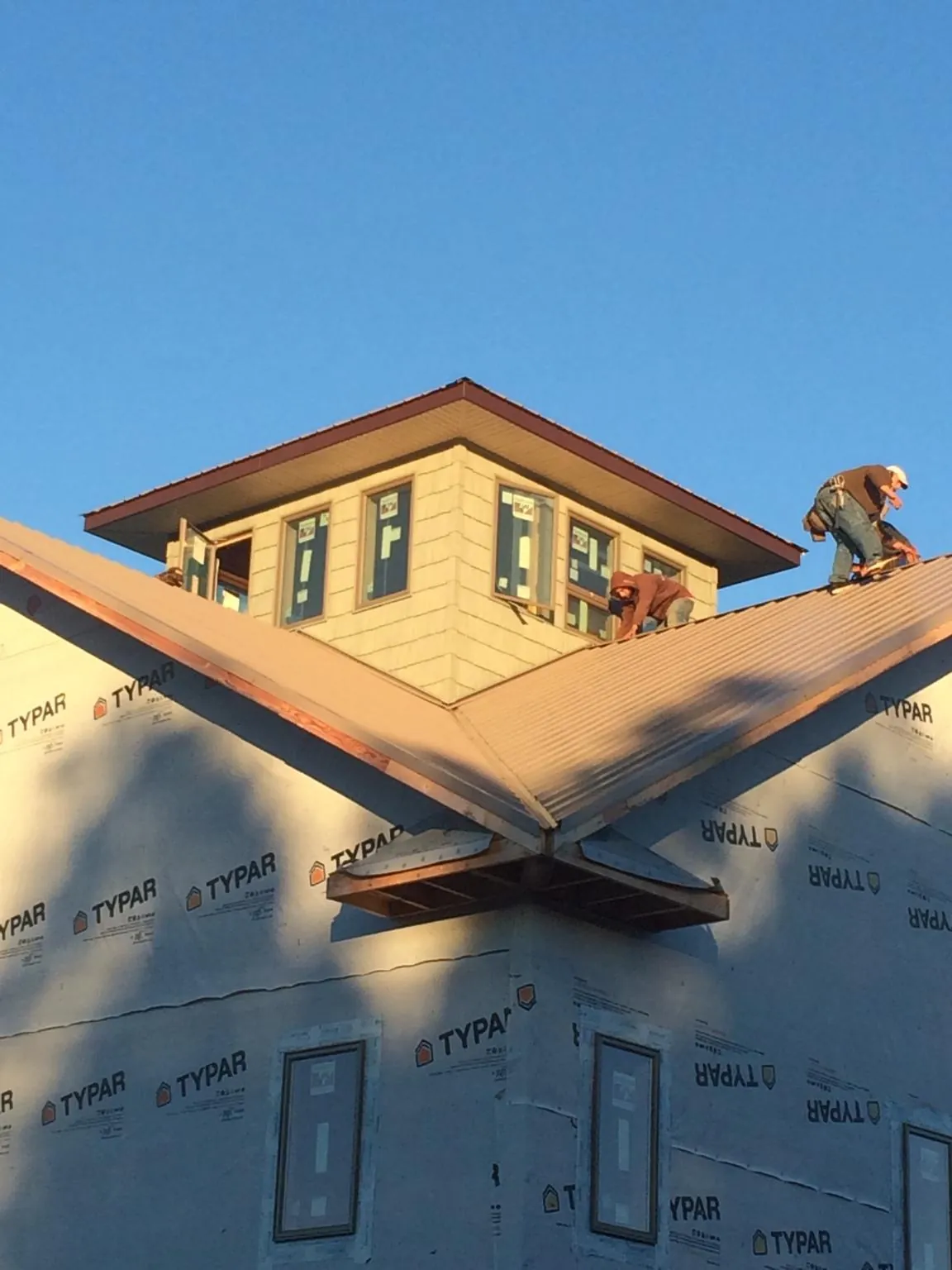 Roofers working around a rooftop cupola on a new metal roof at sunset — Roof Waterproofing in Chula Vista by Roofing Brothers